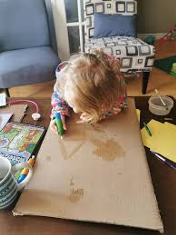 Child water painting on cardboard